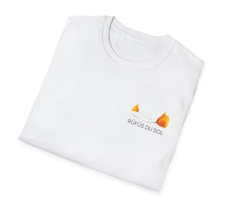 May include: White t-shirt with a small orange flower graphic and the text "R&Uuml;F&Uuml;S DU SOL" printed on the front.