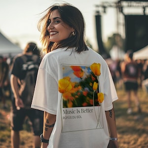 May include: White t-shirt with a graphic print of yellow flowers and the text "Music Is Better" and "R&Uuml;F&Uuml;S DU SOL".