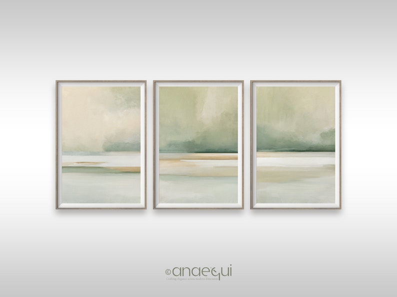 May include: Set of three framed abstract landscape art prints. Each print features a soft color palette of beige, green, and light blue. The artwork has a minimalist style, with horizontal bands of color suggesting a horizon line and sky.