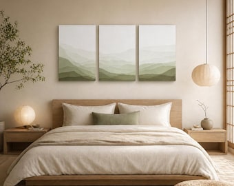 Könnte beinhalten: Schlafzimmer im minimalistischen Design. Mittelpunkt ist ein Holzbett mit weißer Bettwäsche und einem grünen Zierkissen. Über dem Bett befinden sich drei gerahmte Landschaftsbilder in Grüntönen. Eine runde Papierlaterne hängt von der Decke.