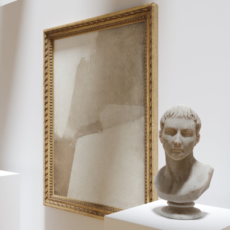May include: A framed abstract painting with a gold ornate frame hangs on a white wall. Beside it, a white bust of a man with short hair sits on a pedestal. The painting features neutral tones.
