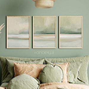 May include: Three framed abstract landscape art prints in muted green, beige, and white tones. The artwork features a minimalist design with horizontal bands of color, evoking a sense of calm. The frames are a light wood color, and the overall aesthetic is modern and serene.