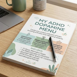 May include: A book titled "My ADHD Dopamine Menu" with a pen on top, featuring sections for appetizers, main courses, and desserts. The book includes minimalist pages, checklists, and ADHD-friendly layouts. A green mug, a succulent, and a laptop are also on the wooden surface.