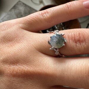 May include: A silver ring with a green and white agate stone set in a leafy design.