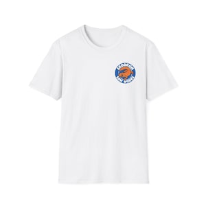 Peut inclure: T-shirt blanc à col rond avec un logo circulaire sur la poitrine gauche. Le logo représente une créature orange ressemblant à un ours avec le texte "SKOOKUM SAW WORKS" en bleu et blanc.