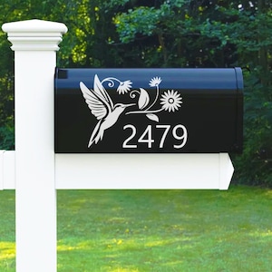 May include: Black mailbox with a white hummingbird and floral design. The mailbox has the number 2479 on it.