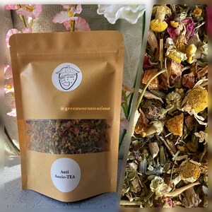 Puede incluir: Una bolsa de papel marr&oacute;n con una ventana transparente que muestra una mezcla de hierbas secas, flores y trozos de fruta. La bolsa tiene una etiqueta que dice "Anti Anxie-TEA" y un logotipo con una fresa y el texto "@greenwormteatime".