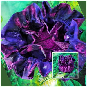 Könnte beinhalten: Eine lila und blaue Tasche mit Galaxie-Druck und Kordelzug mit lilafarbener Innenausstattung. Die Tasche ist offen und die Innenausstattung ist sichtbar. Die Tasche liegt auf einer grünen Oberfläche.