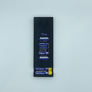Peut inclure: Un porte-piles noir avec le texte "AA" sur le devant. Le porte-piles est rempli de huit piles AA, toutes étiquetées "Varta Industrial Pro" et "Made in Germany".
