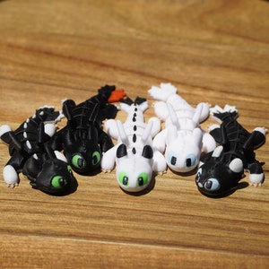 May include: Four small dragon figurines, two black with white accents and two white with black accents. The dragons have green eyes and are posed in a playful manner.