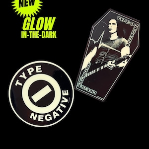 May include: Two glow-in-the-dark stickers featuring Type O Negative branding. One is a circular black and white logo sticker. The other is a coffin-shaped sticker depicting a musician with a guitar, the text LIFE IS KILLING ME, and TYPE O NEGATIVE.