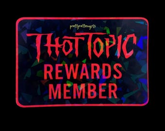 May include: A rectangular sticker with a black background and a red border. The sticker has the words "THOT TOPIC REWARDS MEMBER" in red, stylized lettering. The background has a holographic, geometric pattern. The text "prettyrottengirls" is in the top left corner.