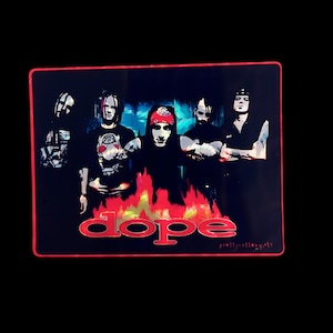 May include: A rectangular sticker featuring a band portrait against a black background. The band members are in black and white, with a red border. The word "dope" is in red, with "prettyrottengirls" in small text.