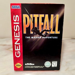 May include: A red, white, and black Sega Genesis game cartridge box for Pitfall: The Mayan Adventure. The box features a silhouette of a person swinging on a rope with the game title in large yellow letters.