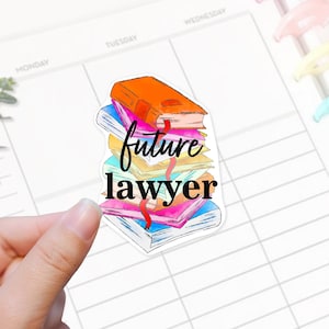 May include: A sticker featuring a stack of colorful books with the words "future lawyer" in a handwritten font. The books are in shades of orange, pink, blue, and yellow, with a red ribbon bookmark.
