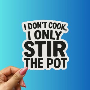 May include: White sticker with the text "I DON'T COOK, I ONLY STIR THE POT" in a bold, black font. The sticker is held by a hand with pink nail polish against a blue gradient background.