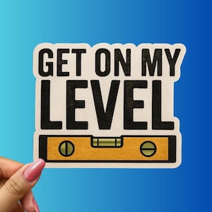 May include: A sticker with the text "GET ON MY LEVEL" in black, above a yellow level tool graphic. The sticker has a white background and is held by a hand with pink nail polish against a blue gradient background.