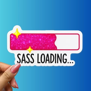 May include: A white sticker with a pink glitter-filled loading bar and the text "SASS LOADING...". The loading bar has two yellow star accents. The sticker is held by a hand against a blue gradient background.
