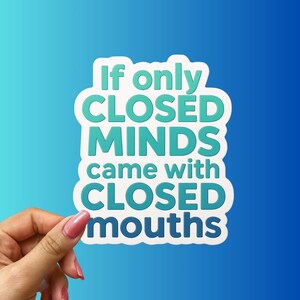May include: A white sticker with the text "If only CLOSED MINDS came with CLOSED mouths" in teal and white. The sticker is held by a hand with pink nail polish against a blue gradient background.