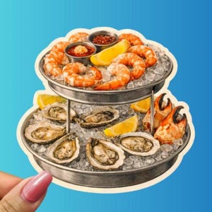 May include: A two-tiered seafood platter sticker featuring shrimp, oysters, crab claws, and lemon wedges. The seafood is arranged on ice in metal trays, with small bowls of dipping sauce. The sticker has a blue background.