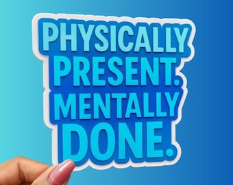 May include: A sticker with the text "PHYSICALLY PRESENT. MENTALLY DONE." in shades of blue, outlined in white. The sticker is held by a hand with a pink nail polish.