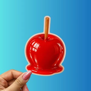 May include: A glossy red candy apple with a wooden stick, set against a gradient blue background. The apple has a smooth, reflective surface and a light-colored outline. A classic treat.