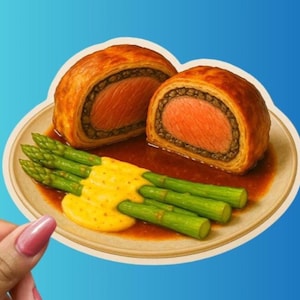 May include: A cut-open Beef Wellington with a flaky, golden-brown crust, revealing a pink center. Served with green asparagus and a yellow sauce on a beige plate, against a blue background.