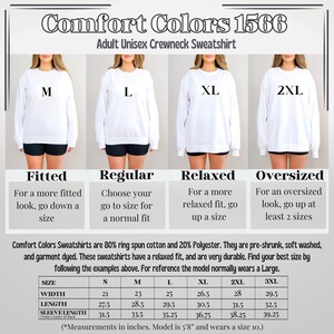 Puede incluir: Una tabla de tallas para una sudadera con cuello redondo unisex de Comfort Colors. La tabla muestra las medidas en pulgadas para diferentes tallas, incluyendo el ancho, la longitud y la longitud de la manga. La modelo mide 1,73 m y lleva una talla 10.