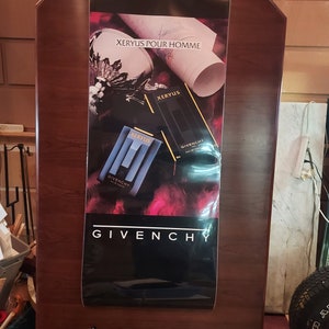 May include: A black and white poster advertising Givenchy's Xerus Pour Homme cologne. The poster features a black and gold bottle of cologne with the words "Xerus Pour Homme" and "Givenchy" printed on it.
