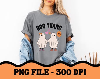 May include: A gray t-shirt with the text "BOO THANG" printed on it. The shirt features a graphic of two ghosts holding hands with a pumpkin balloon.