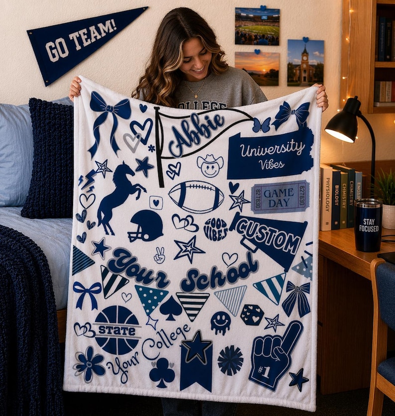 May include: A white fleece blanket with navy blue graphics, including a football, stars, and the words "University Vibes" and "Your School". The blanket has a personalized name banner.