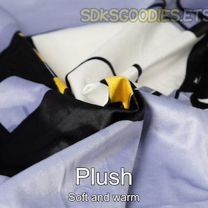 K&ouml;nnte beinhalten: Nahaufnahme eines weichen, pl&uuml;schigen Stoffes in Blaut&ouml;nen, Schwarz, Wei&szlig; und Gelb. Der Stoff hat eine strukturierte, flauschige Oberfl&auml;che und wird als "Plush, Soft and warm" beschrieben.