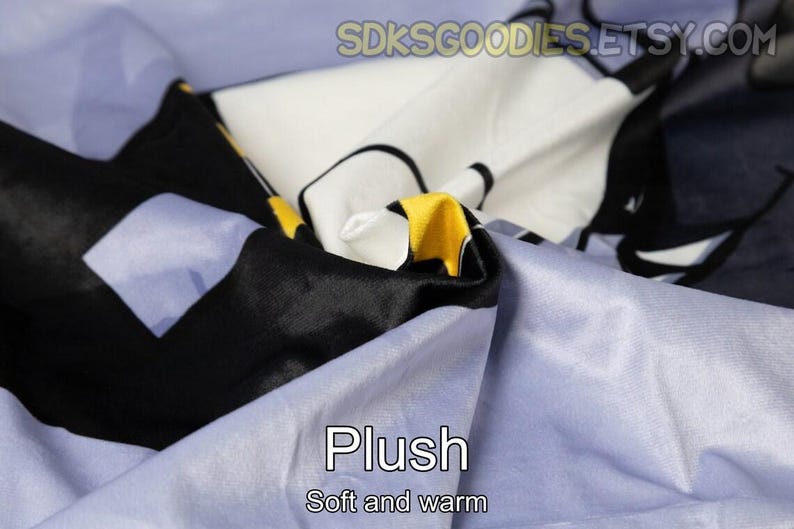 K&ouml;nnte beinhalten: Nahaufnahme eines weichen, pl&uuml;schigen Stoffes in Blaut&ouml;nen, Schwarz, Wei&szlig; und Gelb. Der Stoff hat eine strukturierte, flauschige Oberfl&auml;che und wird als "Plush, Soft and warm" beschrieben.