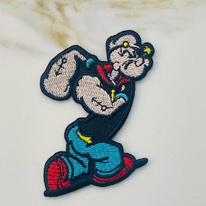 May include: An embroidered iron-on patch featuring a cartoon sailor man with a black hat, red collar, and blue pants. He is running with his arm outstretched and a determined expression on his face.