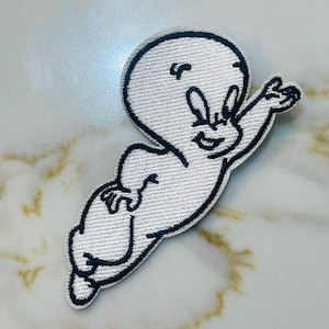 May include: White embroidered patch of a cartoon ghost with a smiling face and outstretched arm. The ghost is outlined in black thread.