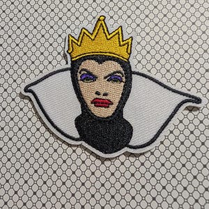 May include: Embroidered patch featuring a stylized portrait of a queen wearing a gold crown. The queen has purple eyeshadow, red lips, and a black collar. The patch is outlined in white.