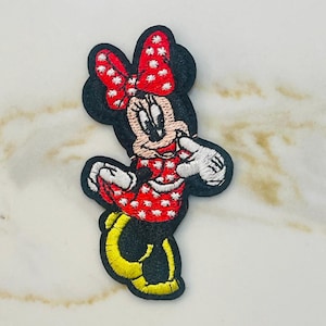 May include: Red and white polka dot embroidered iron-on patch of Minnie Mouse with a yellow bow.