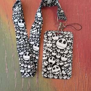 May include: A black and white lanyard and ID holder set. The lanyard and ID holder feature a repeating pattern of Jack Skellington's face from The Nightmare Before Christmas. The set includes a metal clasp and a black string.