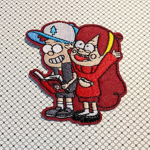 May include: Embroidered patch featuring two cartoon characters, one wearing a blue and white cap with a tree emblem, the other in a red sweater. The patch has a red border and is on a patterned background.