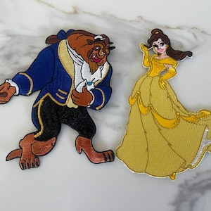May include: Embroidered iron-on patches of Belle and the Beast from Disney's Beauty and the Beast. Belle is wearing a yellow gown and Beast is wearing a blue jacket with gold trim.