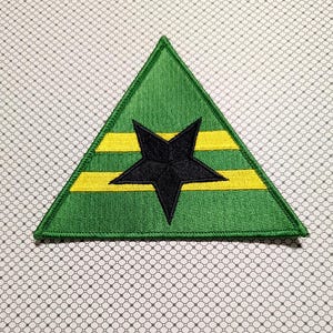 May include: A green, yellow, and black embroidered patch in a triangular shape. The patch features a black star in the center, with two yellow horizontal stripes. The background is green.