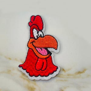 May include: Red embroidered iron-on patch of a cartoon rooster with a wide open beak and a pink tongue.