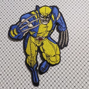 May include: Embroidered patch featuring the Marvel Comics character Wolverine. The patch depicts Wolverine in a dynamic pose, with his claws extended. The design uses yellow, blue, and black thread, with a detailed, comic book style.