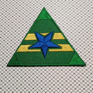 May include: Green triangular patch with a blue star in the center and gold horizontal stripes. The patch is embroidered with a detailed design and has a textured appearance. The patch is likely for clothing or accessories.