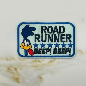 May include: A blue and white embroidered patch featuring the Road Runner cartoon character with the text "Road Runner" and "Beep! Beep!" with five stars.