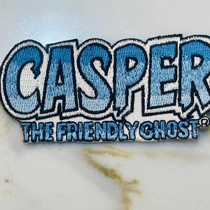 May include: Blue and white embroidered patch with the text "Casper The Friendly Ghost" in a white outline.