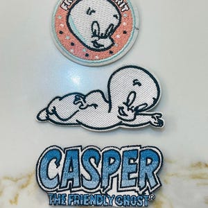 May include: Three embroidered iron-on patches featuring Casper the Friendly Ghost. The first patch is a circle with a pink background and white polka dots. The second patch is a white Casper lying on his side. The third patch is a blue gradient with the text "Casper The Friendly Ghost".