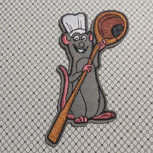 May include: Embroidered patch featuring a cartoon rat wearing a chef's hat and holding a wooden spoon. The rat is gray with pink accents, and the spoon is brown and orange. The patch is on a patterned background.
