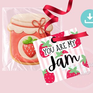 May include: A strawberry jam cookie in a clear bag, tied with a red ribbon, next to a tag that says "You Are My Jam" with strawberry illustrations. The cookie is shaped like a jar with a strawberry design.