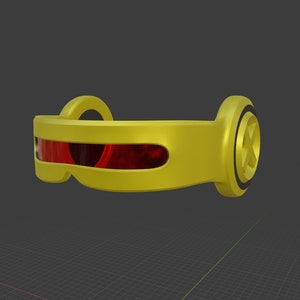 May include: A yellow visor featuring a horizontal red lens across the front and a circular side panel embossed with a large letter X. The frame is smooth and curved, designed to wrap around the head, with a distinct black ring detail on the side.